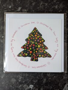 rainbow coloured paint droplets within a christmas tree shape. O christmas tree lyrics surround it in a circle